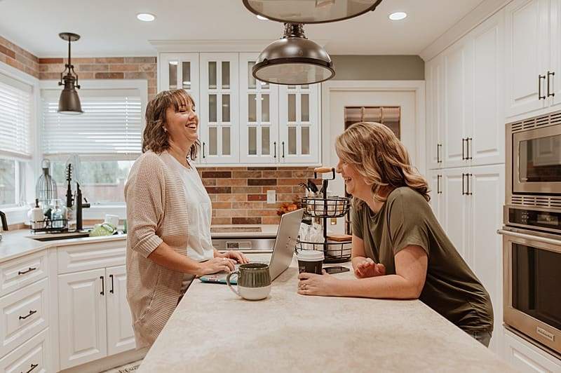 Entrepreneurs laughing while working in a bright creative space — personal branding portrait showing authenticity and warmth.