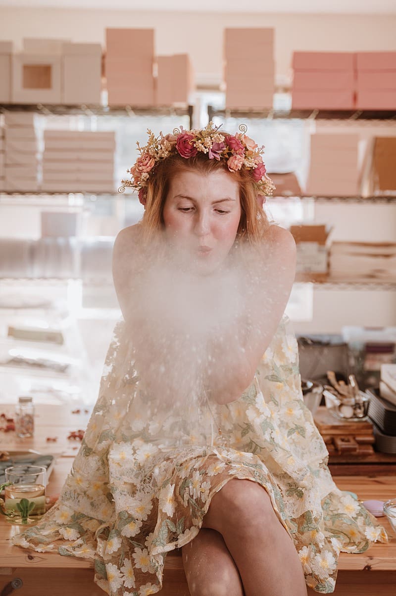 Kizzy blowing icing sugar in her bakeshop during brand photo shoot in Maple Ridge