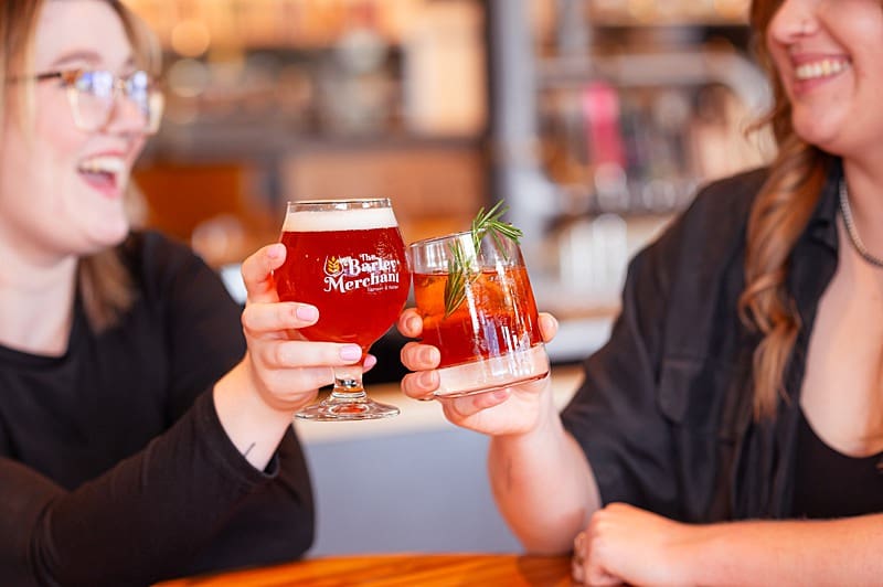 two ladies at Langley's The Barley Merchant clinking glasses during a brand photoshoot.
