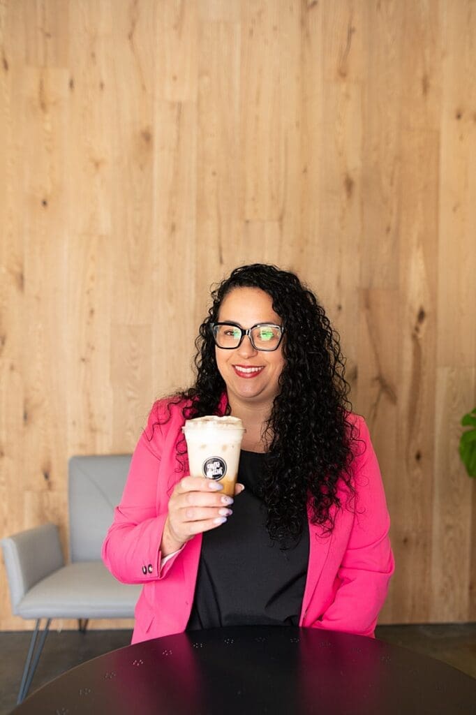 Lifestyle portrait of Jenna, owner of Caffe Delish enjoying a coffee in her cafe.