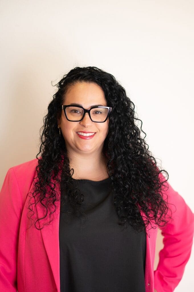Headshot of female business owner dressed in a bright pink blazer smiling at the camera with Kindred Brand Imagery, Headshot photographer
